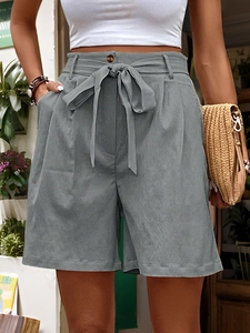 Detail of high-waisted dark grey shorts featuring a fabric bow belt and wood button