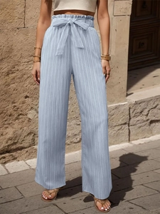 Dettaglio dei pantaloni plissettati celesti a gamba larga con vita alta elastica e fiocco