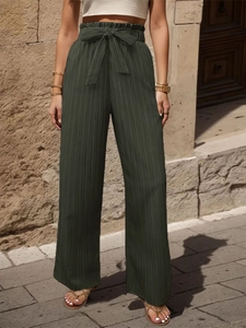 Dettaglio dei pantaloni a vita alta verde scuro con tessuto a pieghe e fiocco in vita