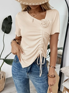 Dettaglio del top beige in maglia a coste con fiore 3D e coulisse laterale arricciata
