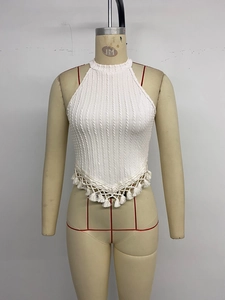 Detail of white knit halter top featuring cable knit patterns and fringe tassel hem
