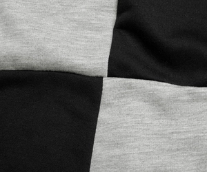 Close-up of black and grey contrast knit fabric showing soft hooded dress texture