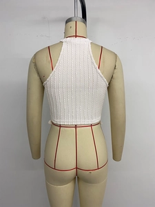Detail of white cable knit halter top featuring backless cut and cropped slim fit