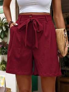 Detail of high waisted burgundy shorts featuring a matching bow belt for summer casual wear