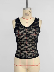 Detailed close-up of floral hollow lace fabric with bow knot on black camisole top