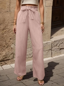 Dettaglio dei pantaloni a gamba larga pieghettati a vita alta con fiocco e volant