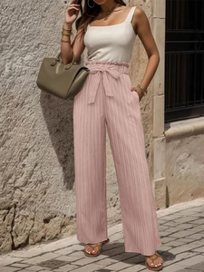 Dettaglio dei pantaloni plissettati a vita alta rosa con fiocco decorativo in vita