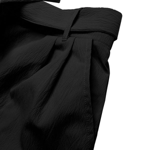 Close-up of black high-waisted shorts with pleated detail and textured fabric finish