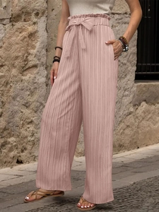 Dettaglio dei pantaloni plissettati a vita alta a gamba larga con fiocco rosa abbinato