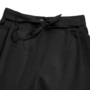 Close-up of high-waist summer shorts featuring a bow-tie belt and fine fabric texture
