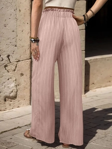 Dettaglio di pantaloni larghi a pieghe a vita alta con elastico in vita a balze color rosa cipria