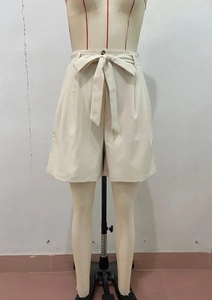 Detail view of high waist summer shorts in beige with stylish tie-knot bow and dark button