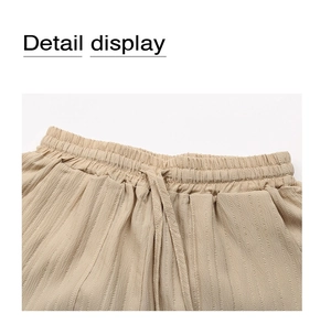 Detail display of beige high-waisted shorts with elastic drawstring and pleated texture