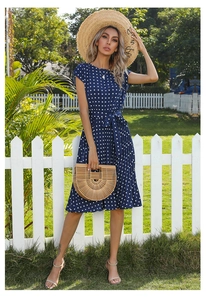 Detail of navy blue polka dot pleated midi dress with waist tie and round neckline