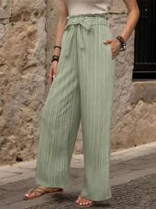 Dettaglio dei pantaloni a gamba larga pieghettati a vita alta con cintura annodata