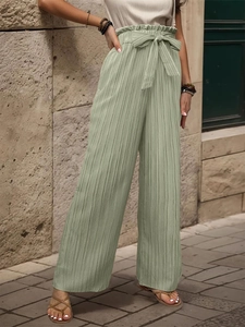 Dettaglio dei pantaloni a gamba larga verde chiaro a vita alta con trama plissettata e cintura