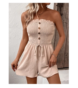 Detail view of the smocked bodice and wooden buttons on the beige strapless jumpsuit