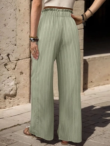 Dettaglio dei pantaloni a gamba larga verde salvia a vita alta con trama plissettata ed elastico