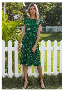 Detail view of a dark green polka dot dress with pleated skirt and matching fabric belt