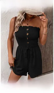 Detailed view of black smocked strapless romper with wooden buttons and waist tie detail