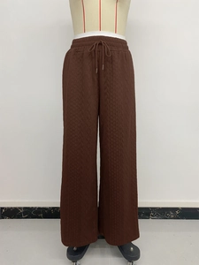 Detail view of brown wide-leg trousers featuring vertical knit texture and drawstring waist