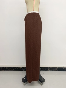 Detail of high waisted brown knit trousers showing cable weave texture and drawstring