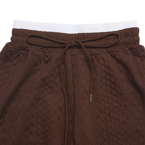 Detail of high waist drawstring on dark brown quilted wide leg trousers with textures