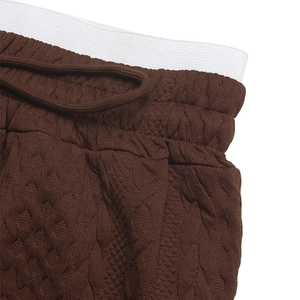 Close-up of high-waist drawstring with diamond quilted texture on brown wide leg trousers