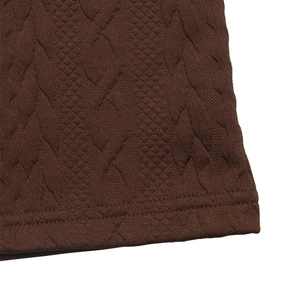 Macro view of dark brown knitted wide leg pants with intricate cable knit texture detail