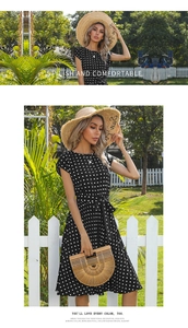 Detail of a black polka dot dress featuring a waist tie and elegant pleated midi skirt
