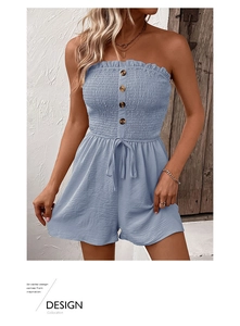 Detailed close-up of smocked light blue summer romper with ruffles and wooden buttons