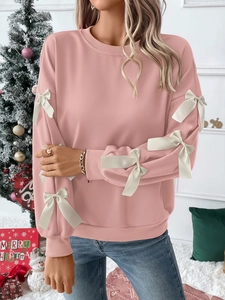 Detail of pink long-sleeve Christmas sweatshirt with 3D white bows on sleeves