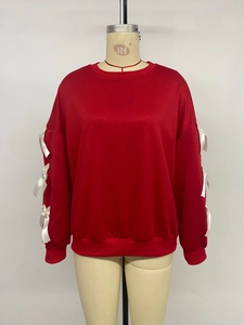 Detail of red crewneck sweatshirt featuring white decorative bows on the sleeves