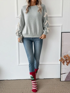 Detail of grey crewneck sweatshirt with delicate cream satin bows on the long sleeves