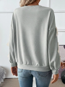 Detailed back view of a grey crewneck sweatshirt featuring ribbon bow sleeves with denim jeans