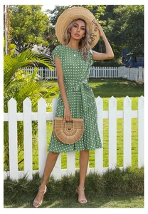 Detail of green polka dot summer dress with waist tie belt and breathable fabric texture