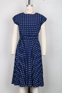 Close-up detail of the pleated hem and navy blue polka dot pattern on the summer dress