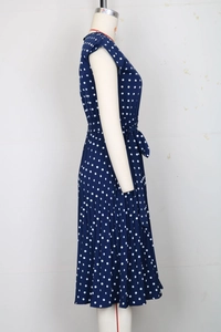 Detailed view of dark blue polka dot midi dress showing pleated skirt and waist tie