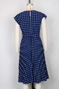 Rear view of navy blue polka dot pleated midi dress on mannequin with back slit button