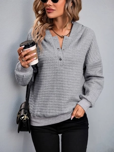 Close-up of gray quilted texture hoodie featuring a silver-buttoned Henley neckline