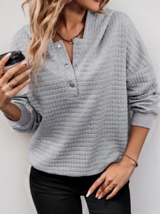 Detail of gray quilted hoodie with textured square pattern and metallic button henley neck