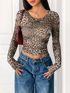 Dettaglio del top aderente a maniche lunghe con stampa leopardata e jeans in denim blu