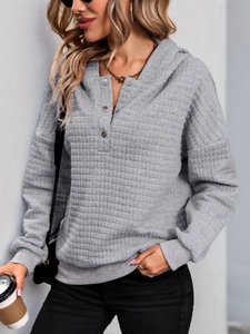 Detailed view of grey textured hoodie showing quilted waffle pattern and silver buttons