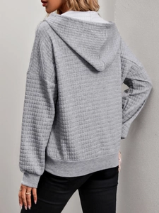 Detail view of the light grey quilted texture and oversized hoodie back silhouette