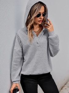 Detail of grey hooded sweatshirt featuring quilted texture and three-button neckline