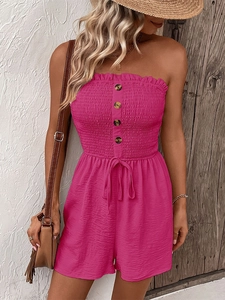 Detail of smocked rose pink romper featuring wood-texture buttons and drawstring waist