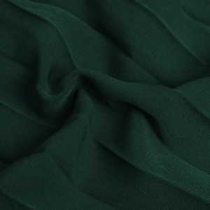 Close-up of deep green pleated fabric showing the fine woven texture and soft folds