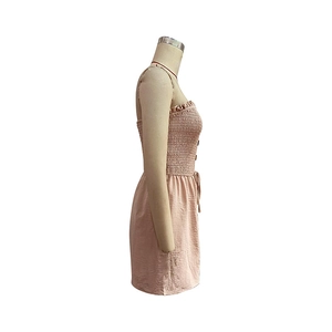 Close-up of smocked bodice and decorative side buttons on a pale pink summer jumpsuit