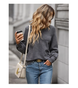 Detailed texture of dark grey textured long sleeve sweatshirt in outdoor setting