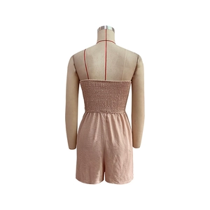Detail view of the elastic smocked back and spaghetti straps on a pink summer romper